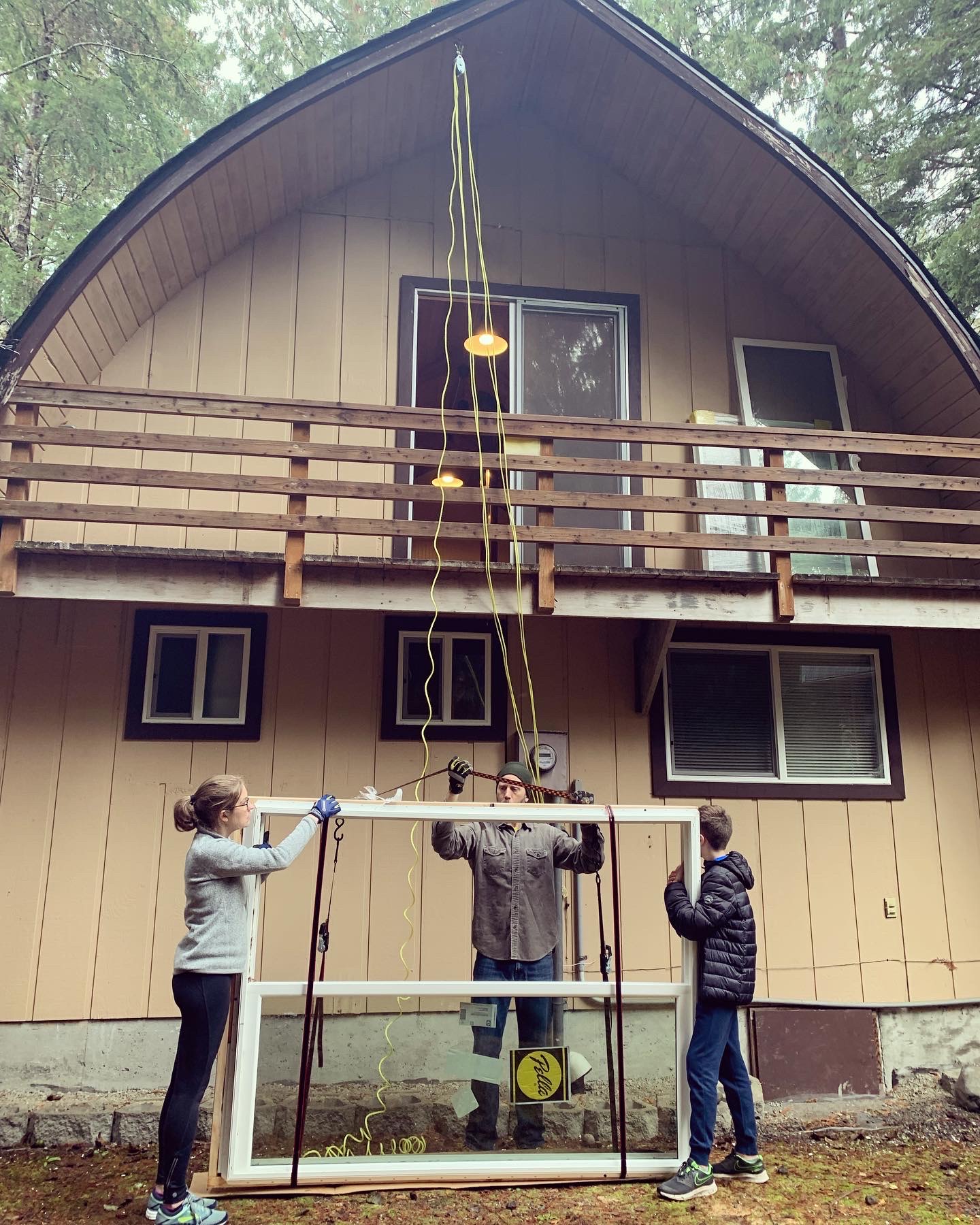 The family hoisting a new sliding glass door up to the second floor with a pulley