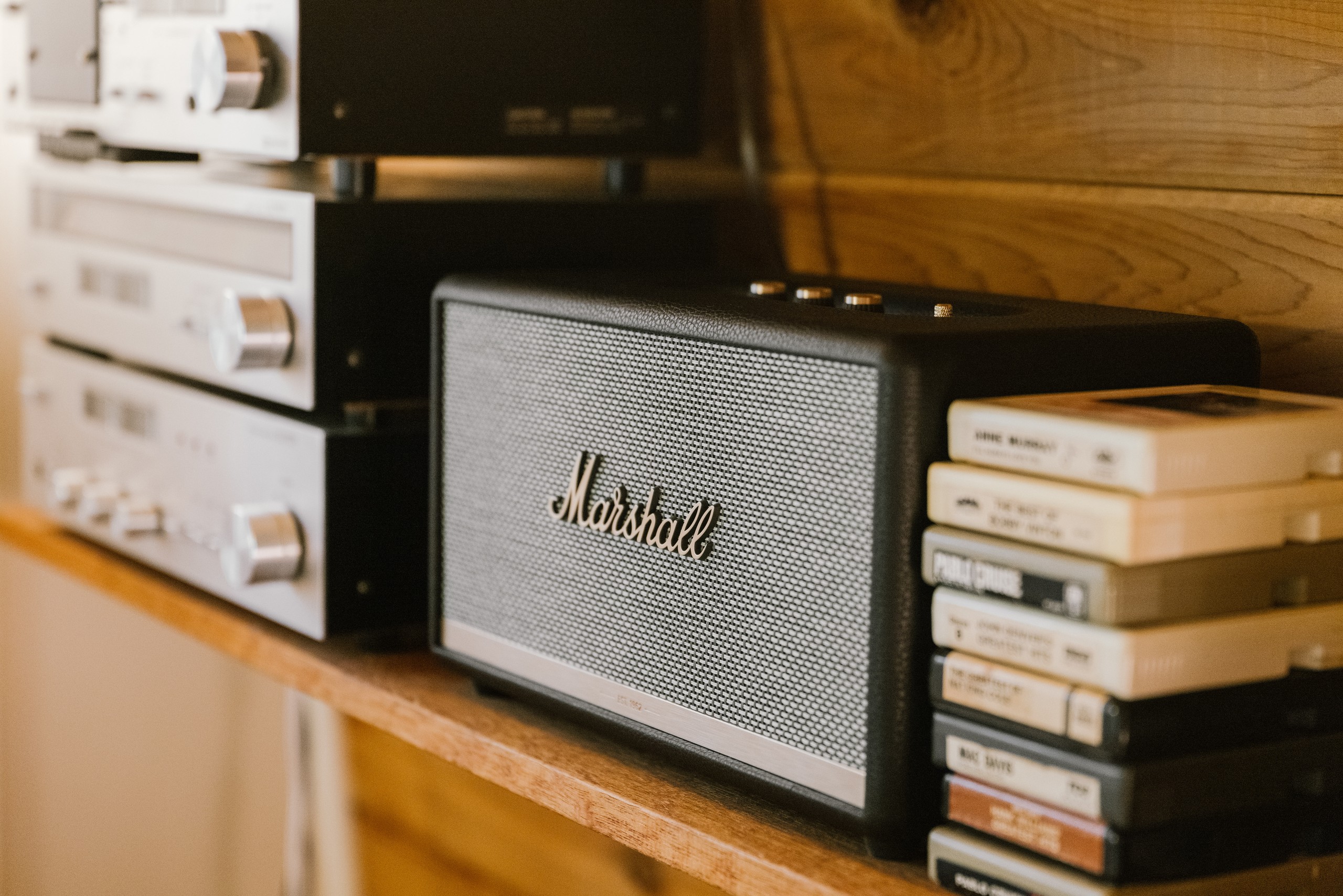 Marshall Bluetooth speaker beside vintage stereo equipment and 8-track tapes