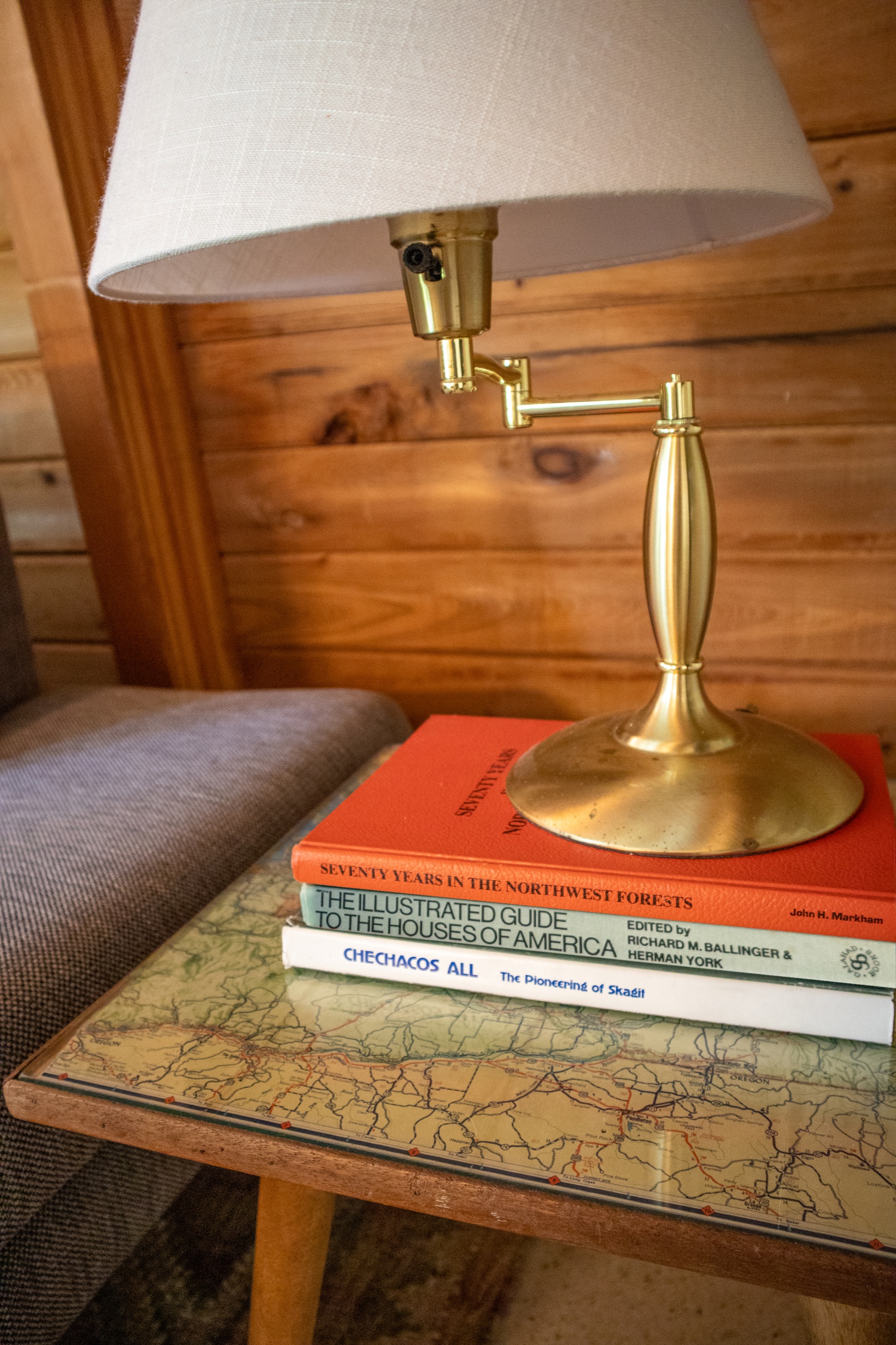 Refinished map-top side table with a brass swing-arm lamp and 1970s books