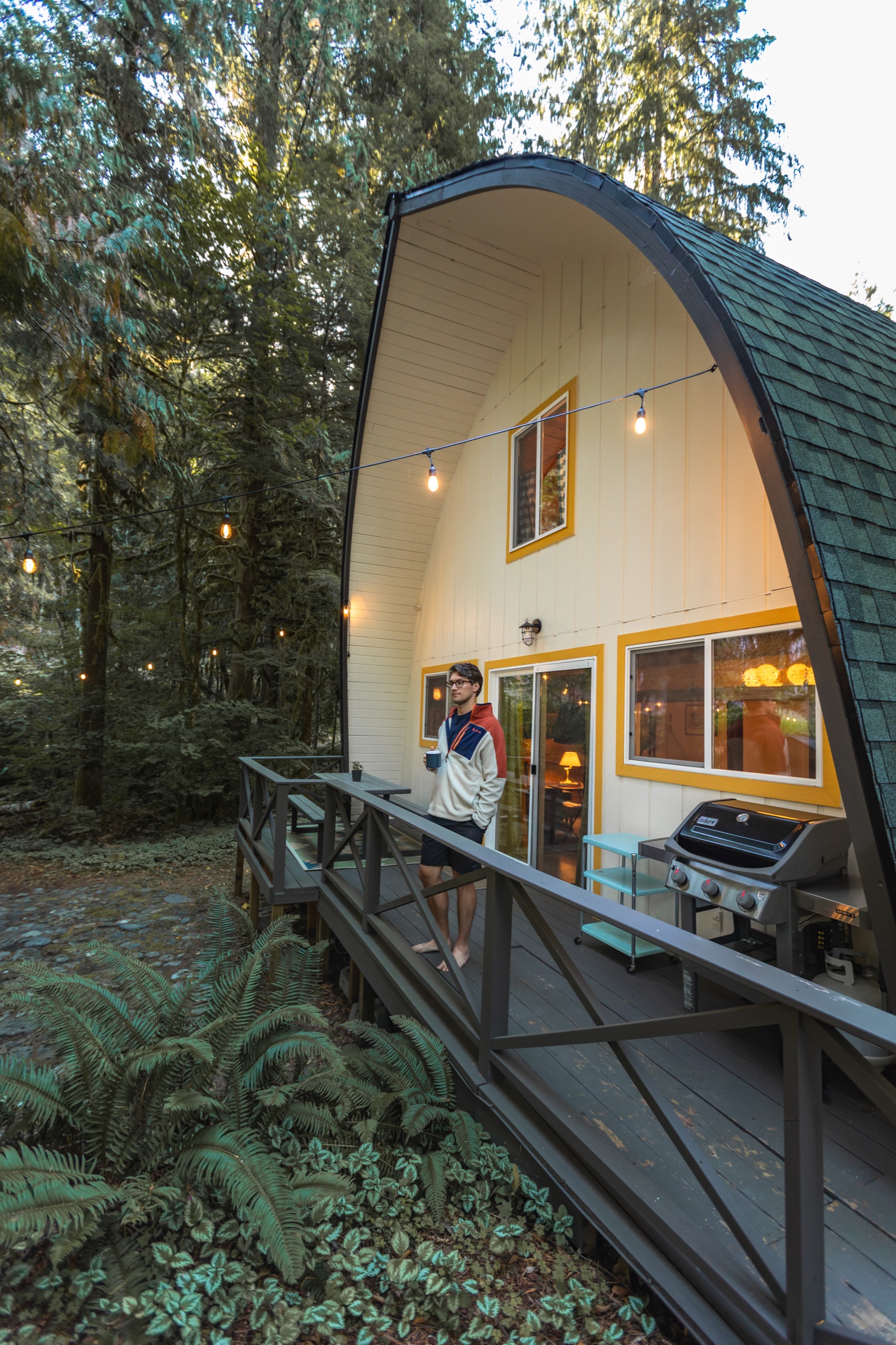 After: the side deck of The Arch House with white siding, yellow trim and string lights