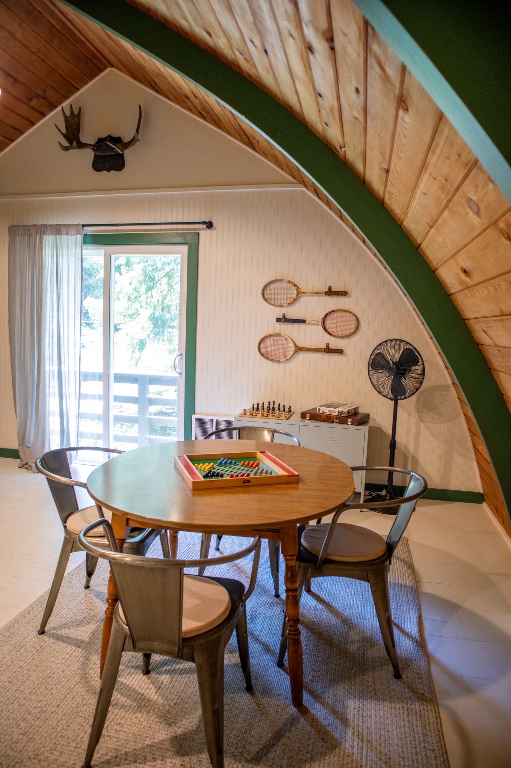 Round game table with metal chairs and vintage tennis rackets on the wall